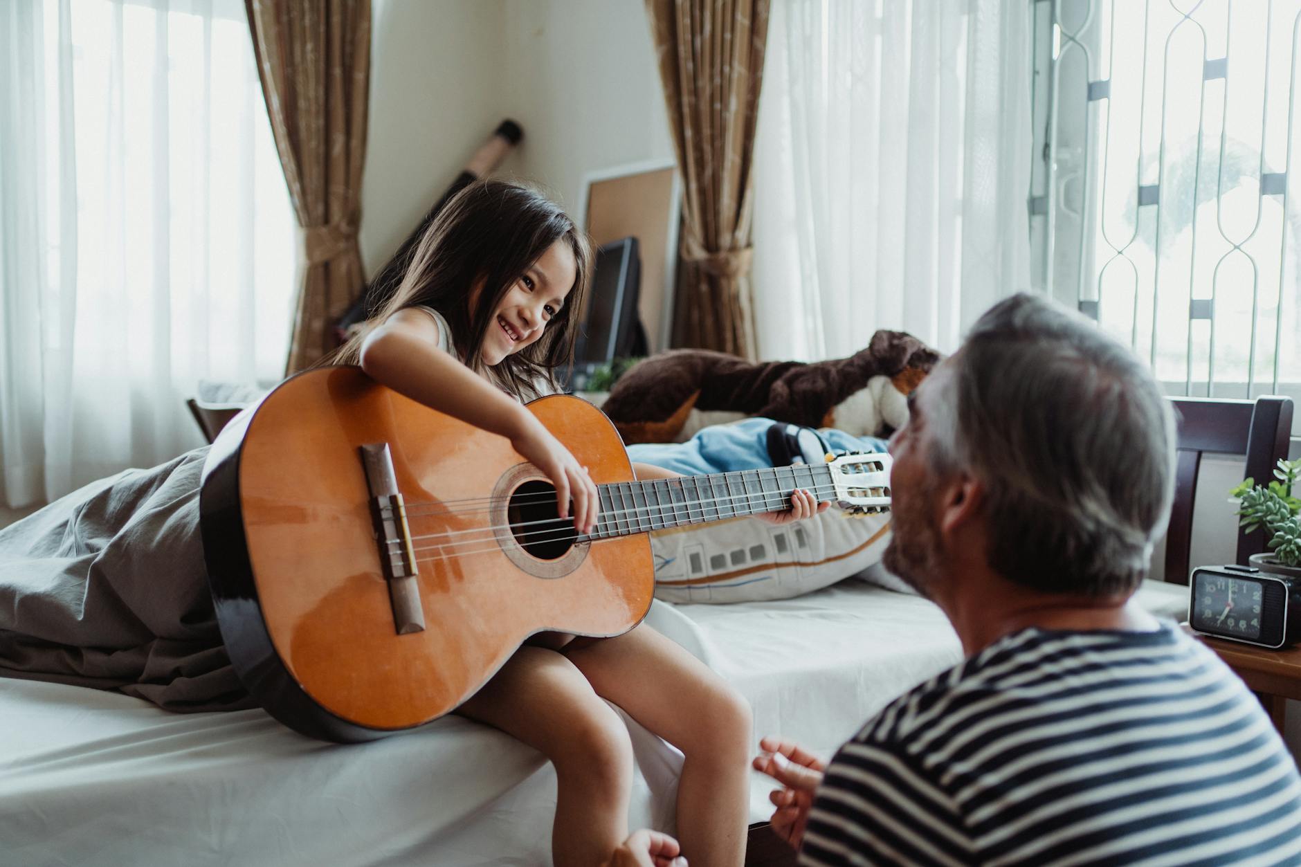 girl playing guitar for her dad